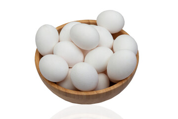 Many eggs lie in a wooden bowl on a white isolated background.