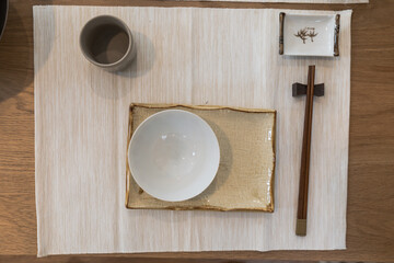 Top view ceramic dish (plate) and chopsticks on white wooden table.