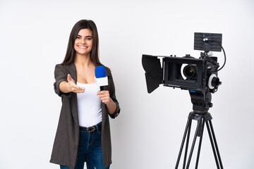 Reporter woman holding a microphone and reporting news over isolated white background handshaking after good deal