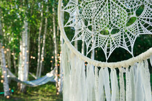 A White Dream Catcher With Trees In A Background