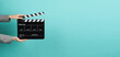 Black Clapperboard or movie Clapper board for videography with hands in grey suit. it use in video production ,movies and cinema industry on green Tiffany Blue background.director film slate