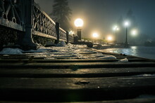 Wooden Bench In The Snow In A Winter Night Park In The Fog. Footpath In A Winter City Park At Night In Fog With Benches And Latterns. Beautiful Foggy Evening In The Mariinsky Park. Kiev, Ukraine.