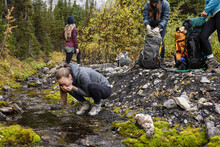 Young Female Hikers Taking A Break At Stream In Autumn Woods