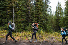 Young Women Friends Backpacking On Trail In Remote Woods