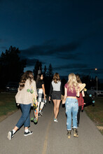 Teenage Girl Friends With Skateboards On Dark Footpath At Night