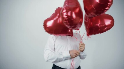 Wall Mural - A funny old man with a beard with red balloons in the form of hearts is dancing merrily at the festival.