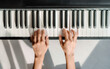 © Maridav - Piano learning chords at home - woman playing digital keyboard with online music lesson. Top view of musician hands on keys.