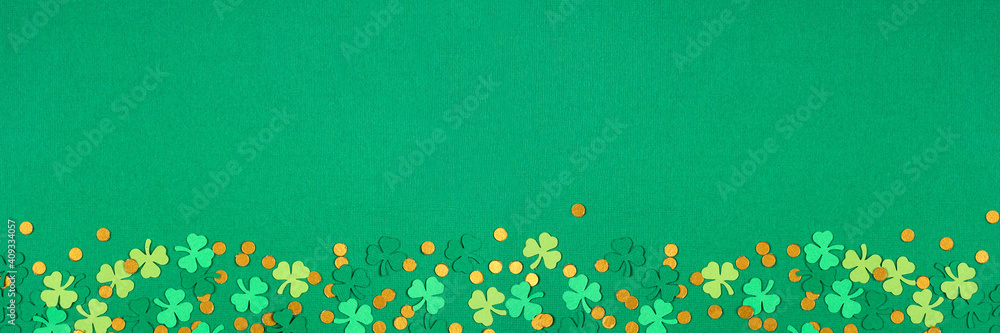St Patricks Day green background with shamrock and gold coin confetti bottom border. Top view banner with copy space. - obrazy, fototapety, plakaty 