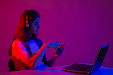 Web design and mobile development, geek guy writes code for a mobile app, portrait in neon light.