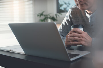 Sticker - Casual business man looking at laptop computer screen taking a coffee break during working from home