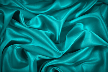 Wall Mural - Blue and green silk satin fabric. Elegant teal color background. Liquid wave or silk soft wavy folds. Beautiful turquoise fabric background with copy space for your design.