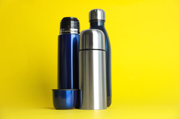 Wall Mural - Stylish stainless thermo bottles on yellow background