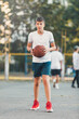 © Natali - Cute young boy plays basketball on street playground in summer. Teenager in white t shirt with orange basketball ball outside. Hobby, active lifestyle, sport activity for kids.