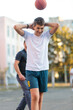 © Natali - Cute young boy plays basketball on street playground in summer. Teenager in white t shirt with orange basketball ball outside. Hobby, active lifestyle, sport activity for kids.