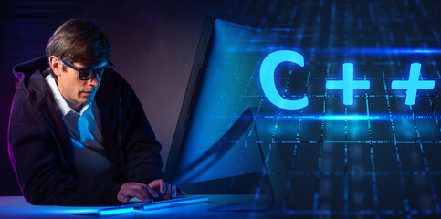 C ++ developer on a dark background. Application development using C ++ language. It will program using c plus plus programming language. Programmer writes code while sitting at computer.