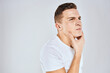 © SHOTPRIME STUDIO - Emotional man in a white t-shirt holds his hand on his face light background