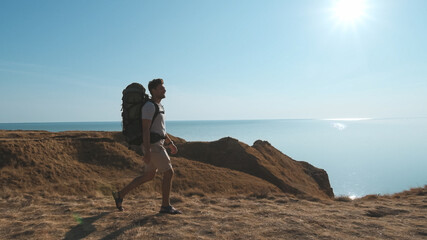 Wall Mural - the happy man with a backpack walking on the mountain against the sea view