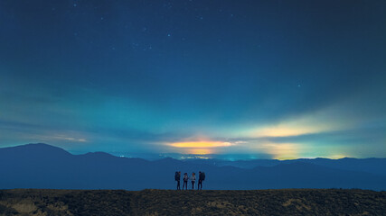 The group of hikers standing on the starry sky background