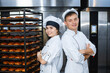 © salomonus_ - Young guy and girl bakers on the background of an industrial oven in a bakery.