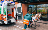 Fototapeta  - Serious and professional team of doctors in the ambulance moving on a patient into the hospital during an emergency situation.