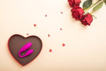 Gift for a woman for Valentine's Day. Clitoral vaginal vibrator in a box in the shape of a heart and a rose on a beige background.