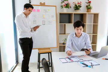 Wall Mural - two asian designer man share ideas mobile phone app development at the office.