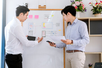 Wall Mural - two asian designer man share ideas mobile phone app development at the office.