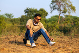 Fototapeta Uliczki - Indian man sitting on rock in open field 