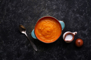 baked pumpkin cream coup with  coconut milk served in nice bowl at wooden black table. flat lay. cooking and healthy life concept