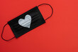 © Studio Roux - Composition for Valentine's Day February 14th. on vibrant red background, black face medical mask white heart. Greeting card flat lay top view copy space. 2021 Love concept covid-19