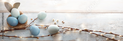 Tender blue easter eggs decorated with pussy willow on gray vintage planks. Horizontal spring background for easter greetings. © gudrun