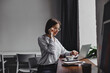 © Look! - Photo of short-haired business woman in glasses and white blouse sitting in workplace and working in laptop