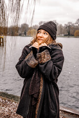 young brunette woman standing outdoors by a lake on snowy day and is freezing