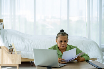 Asian senior retired business woman working at home with Laptop computer in new normal