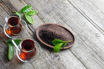 Wall Mural - Glass cup of black tea with fresh and dry tea leaves, traditional turkish brewed hot drink