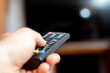 Male hand holding a TV remote and trying to turn on the TV