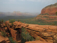 An Unrecognizable Person On Devil's Bridge, The Natural Arch Formation, With Red Rock Mountains In The Background Located In Sedona, Arizona