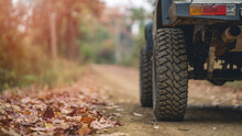 Part Of An Off-road Vehicle On A Rugged Road In The Forest . Travel Concept With Sunset And Mountains. Close Up Photo Of Off Road Wheel. Off-road Travel On Mountain Road.