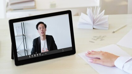 Wall Mural - Virtual conference. Digital meeting. Online interview. Distance communication. Female HR manager watching listening confident Asian man job applicant presentation on tablet screen at light workplace.