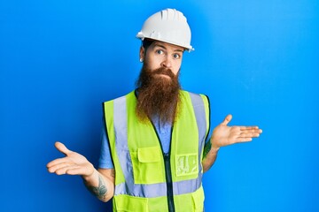 Poster - Redhead man with long beard wearing safety helmet and reflective jacket clueless and confused expression with arms and hands raised. doubt concept.