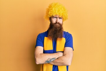 Sticker - Redhead man with long beard football hooligan cheering game wearing funny wig skeptic and nervous, disapproving expression on face with crossed arms. negative person.