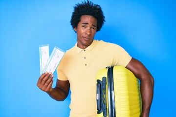 Sticker - Handsome african american man with afro hair holding cabin suitcase and boarding tickets skeptic and nervous, frowning upset because of problem. negative person.