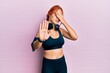 © Krakenimages.com - Young beautiful redhead woman wearing gym clothes and using headphones covering eyes with hands and doing stop gesture with sad and fear expression. embarrassed and negative concept.