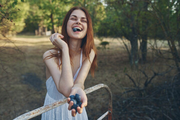 Wall Mural - happy woman with a bunch of grapes leaned on an iron bed outdoors in the garden