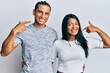 Young latin couple wearing casual clothes smiling cheerful showing and pointing with fingers teeth and mouth. dental health concept.