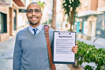 Canvas Print - Young african american businessman smiling happy holding clipboard with agreement document at the city.