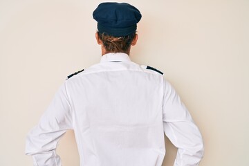 Sticker - Young hispanic man wearing airplane pilot uniform standing backwards looking away with arms on body