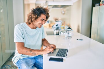 Wall Mural - Young hispanic man smiling happy working using laptop at home