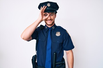 Poster - Young caucasian man wearing police uniform doing ok gesture with hand smiling, eye looking through fingers with happy face.