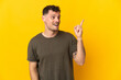 © luismolinero - Young caucasian handsome man isolated on yellow background intending to realizes the solution while lifting a finger up